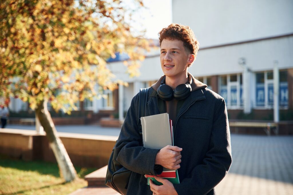 Young student is outside the university, in black clothes